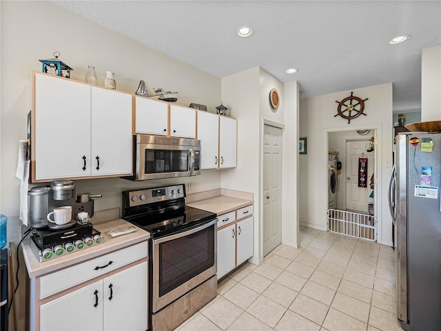 kitchen with light countertops, washer / clothes dryer, appliances with stainless steel finishes, white cabinetry, and light tile patterned floors