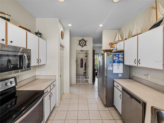 kitchen with white cabinetry, light countertops, light tile patterned flooring, and stainless steel appliances