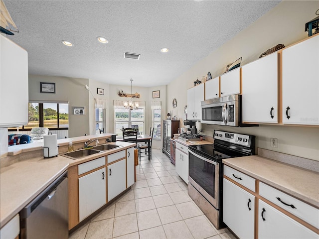 kitchen featuring a sink, stainless steel appliances, light tile patterned floors, visible vents, and an inviting chandelier