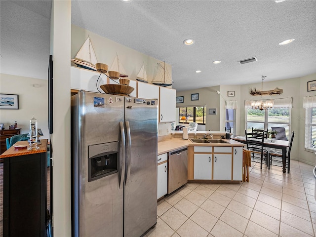 kitchen with stainless steel appliances, light tile patterned flooring, a sink, visible vents, and a notable chandelier