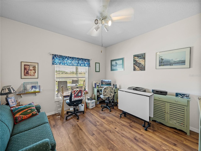 office space featuring baseboards, wood finished floors, and a ceiling fan