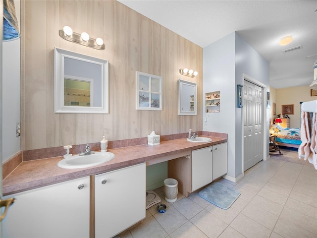 bathroom with ensuite bathroom, double vanity, tile patterned flooring, and a sink