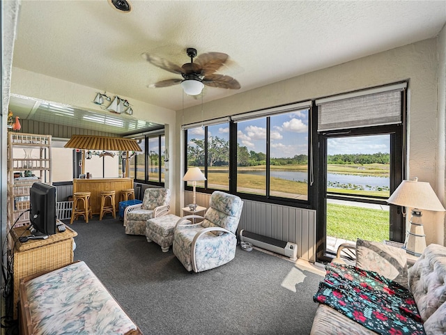 sunroom with a ceiling fan, an outdoor hangout area, and a water view
