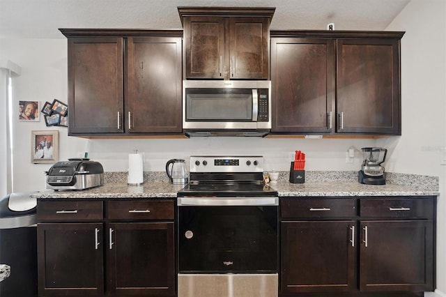 kitchen with dark brown cabinets, stainless steel appliances, and light stone counters