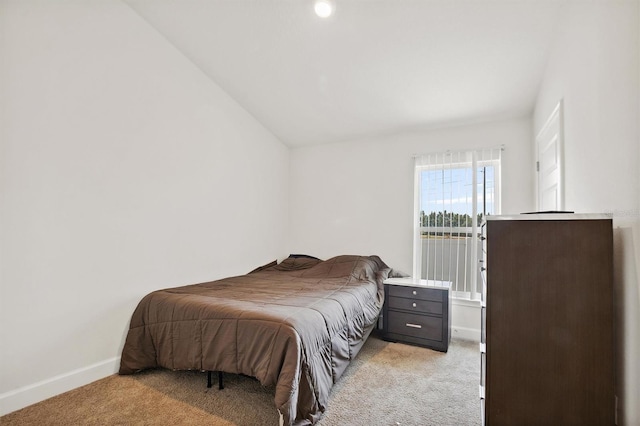 bedroom featuring baseboards, lofted ceiling, and light carpet