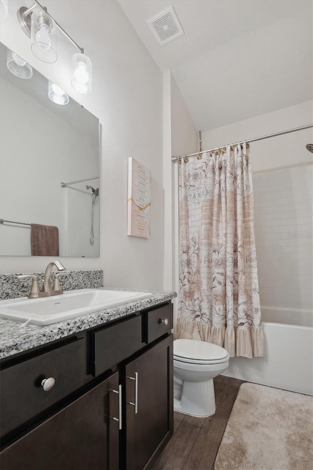 full bathroom featuring vanity, shower / tub combo with curtain, toilet, visible vents, and wood finished floors