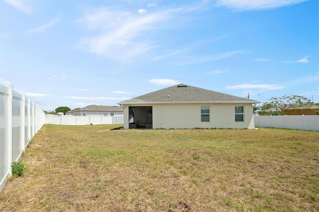 back of house with a fenced backyard, a lawn, and stucco siding