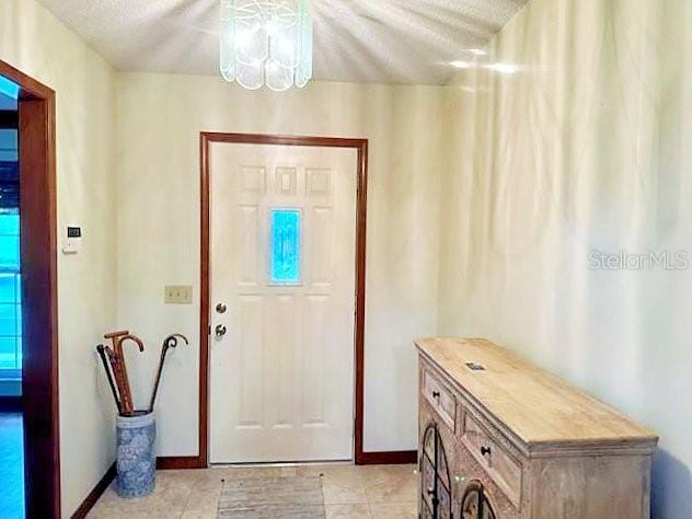 2761 Graniteridge Ct, Orange Park, FL 32065 - doorway to outside featuring light tile patterned flooring, baseboards, and a chandelier