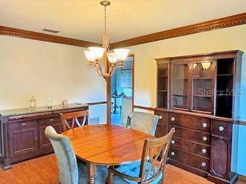 2761 Graniteridge Ct, Orange Park, FL 32065 - dining area with a chandelier, crown molding, and light wood-style floors