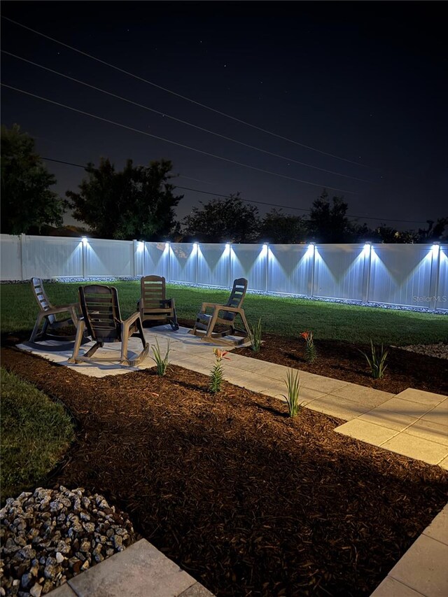 yard at night featuring a patio and a fenced backyard