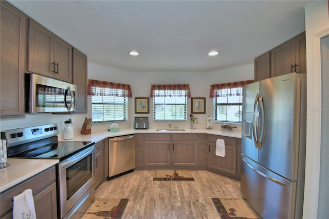 kitchen featuring light wood-style flooring, recessed lighting, appliances with stainless steel finishes, a sink, and light countertops