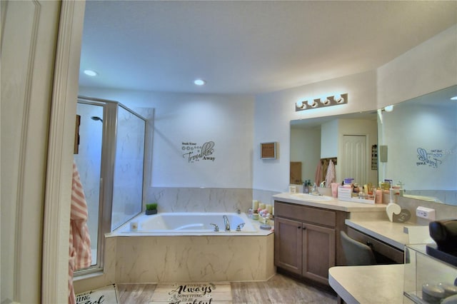 bathroom with a bath, vanity, recessed lighting, a shower, and wood finished floors