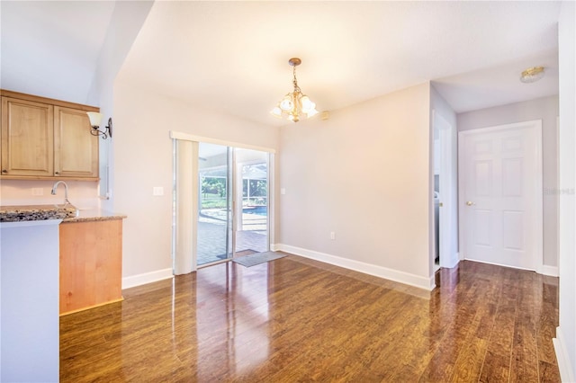unfurnished dining area with a chandelier, dark wood-style flooring, and baseboards
