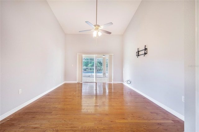 spare room with high vaulted ceiling, a ceiling fan, wood finished floors, and baseboards