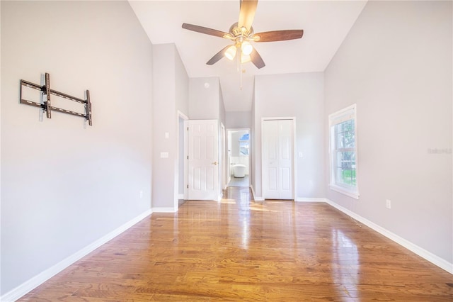 unfurnished bedroom with baseboards, a closet, a ceiling fan, high vaulted ceiling, and wood finished floors