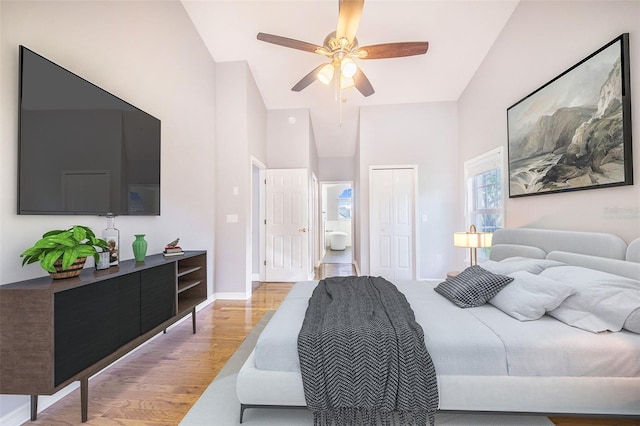 bedroom with light wood-style floors, ceiling fan, a closet, a towering ceiling, and baseboards