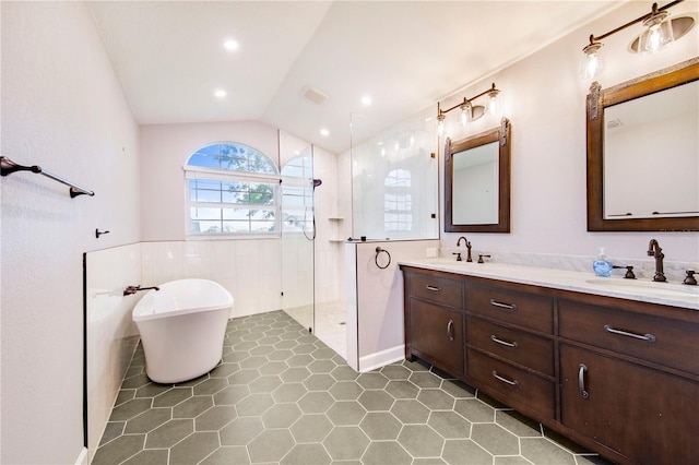 bathroom with a freestanding bath, a walk in shower, a sink, and lofted ceiling