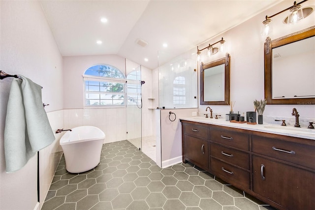 bathroom with a soaking tub, vaulted ceiling, a sink, walk in shower, and double vanity