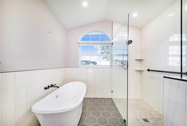 bathroom featuring walk in shower, tile walls, a soaking tub, tile patterned flooring, and lofted ceiling