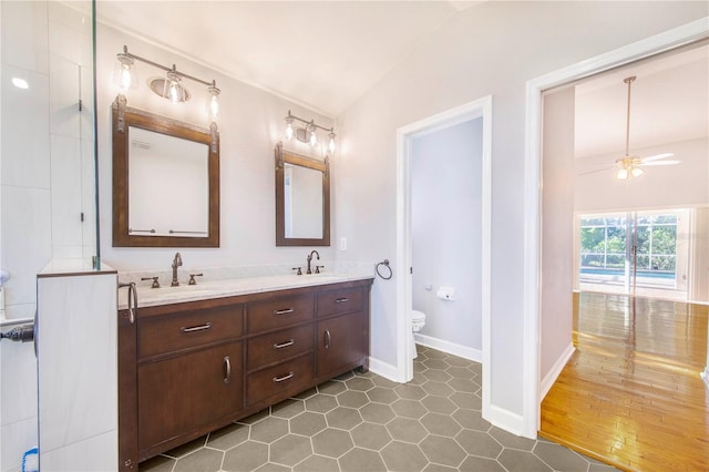 full bath featuring toilet, ceiling fan, double vanity, and a sink
