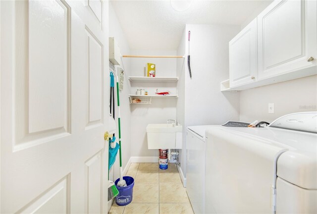 laundry room with cabinet space, light tile patterned floors, washing machine and clothes dryer, and baseboards