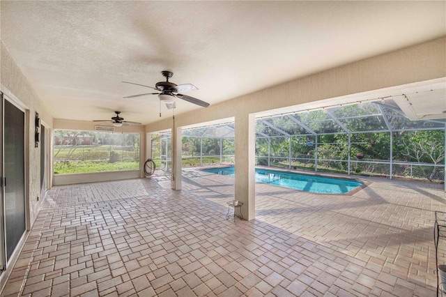 outdoor pool featuring a patio area, glass enclosure, and ceiling fan