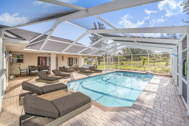 pool with a patio area, outdoor lounge area, a ceiling fan, and glass enclosure