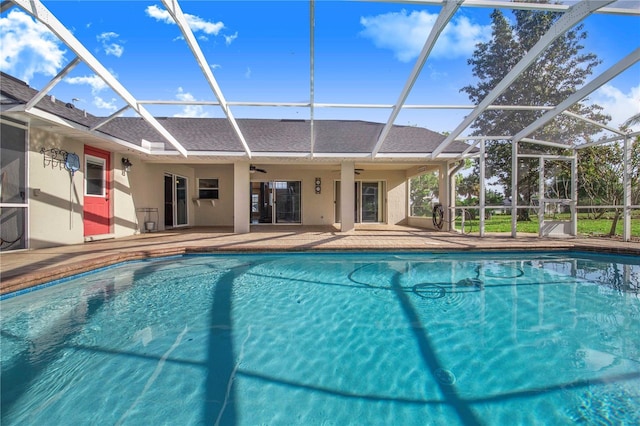 outdoor pool with ceiling fan, glass enclosure, and a patio