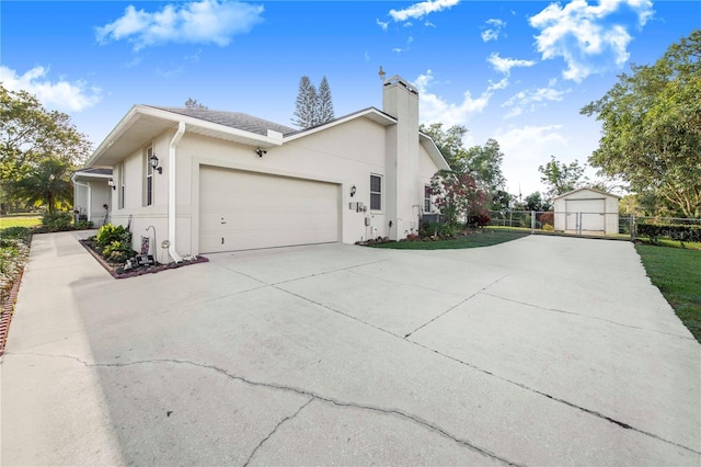 view of side of property with an attached garage, a chimney, fence, stucco siding, and driveway