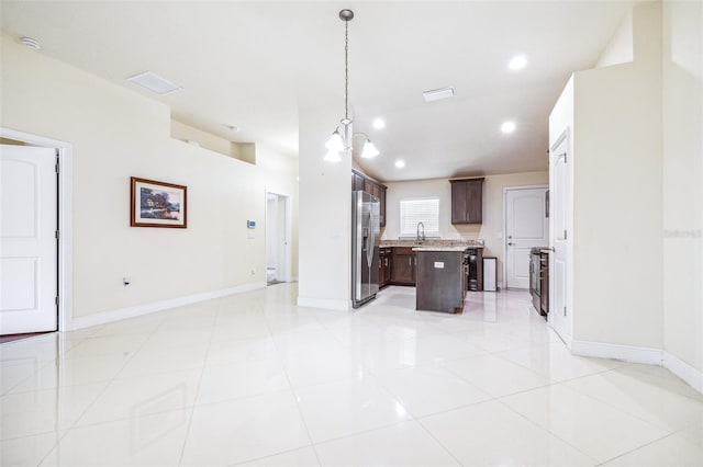 404 Rio Grande Ct, Poinciana, FL 34759 - kitchen with stainless steel fridge with ice dispenser, baseboards, light countertops, dark brown cabinets, and a kitchen island