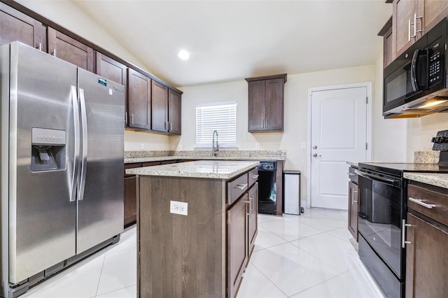 404 Rio Grande Ct, Poinciana, FL 34759 - kitchen with dark brown cabinetry, light tile patterned floors, black appliances, and a kitchen island