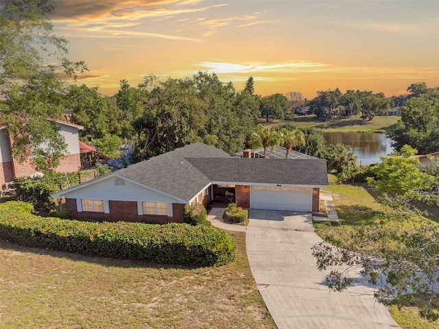 102 Lake Ring Dr, Winter Haven, FL 33884 - view of front of property with a garage, a lawn, a water view, brick siding, and driveway
