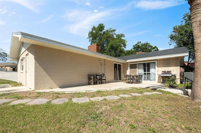 102 Lake Ring Dr, Winter Haven, FL 33884 - back of property with a chimney, a patio area, and a yard