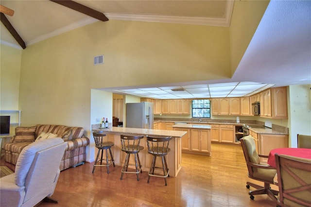 2611 State Road 557, Lake Alfred, FL 33850 - kitchen with light wood-style floors, a kitchen breakfast bar, a peninsula, light brown cabinetry, and appliances with stainless steel finishes