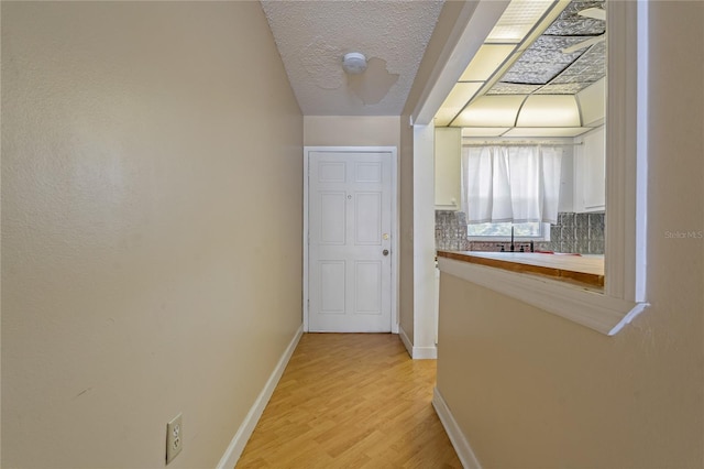 corridor featuring baseboards and light wood finished floors