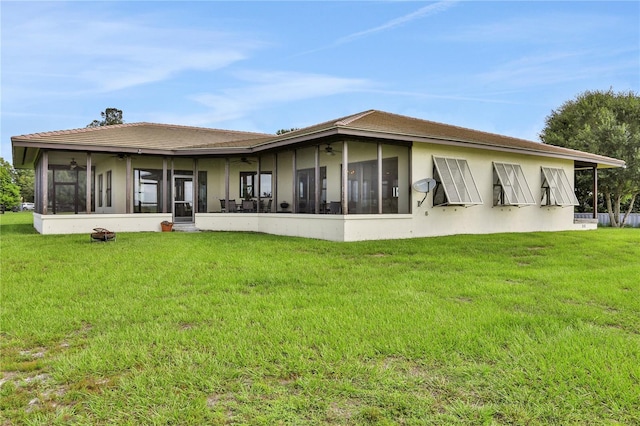 back of house featuring a yard, ceiling fan, a sunroom, and stucco siding