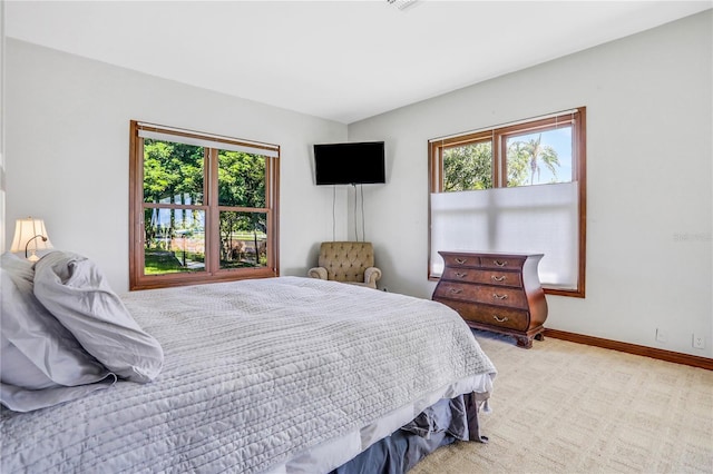 bedroom with baseboards, multiple windows, and light carpet