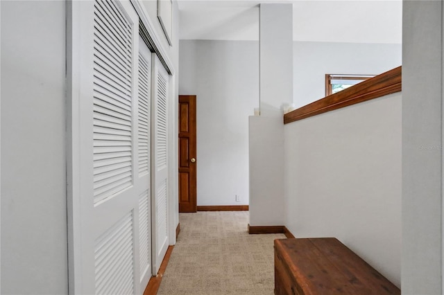 corridor featuring light colored carpet and baseboards