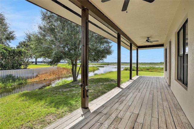deck with a water view, a yard, and ceiling fan