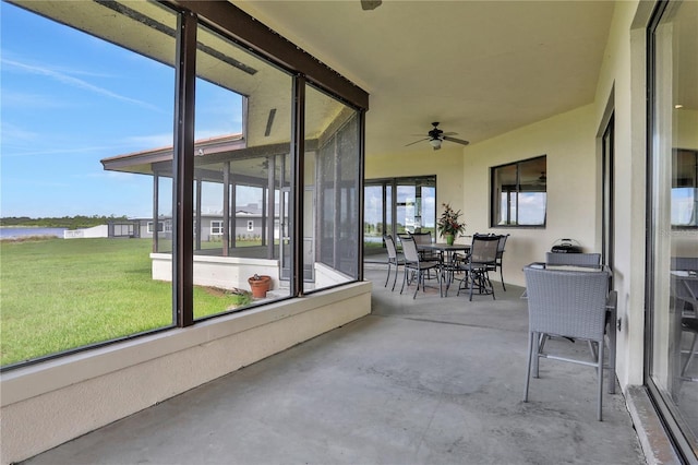 sunroom / solarium with a water view, ceiling fan, and outdoor dining area