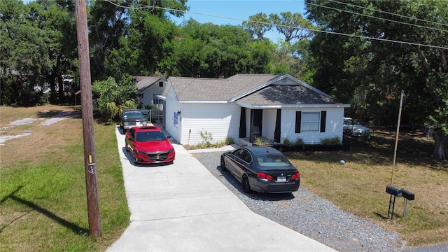 single story home featuring driveway, a shingled roof, and a front yard
