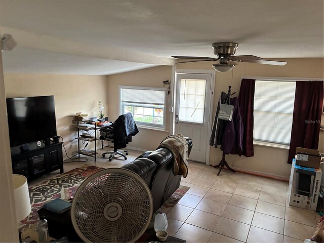 living area featuring light tile patterned flooring, a ceiling fan, and baseboards