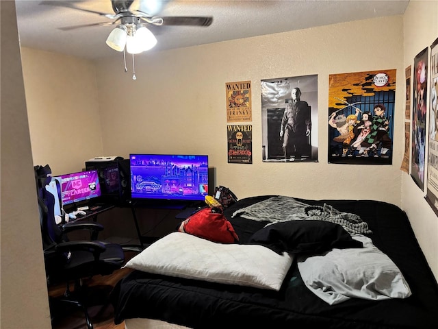 bedroom featuring a ceiling fan, a textured wall, and wood finished floors