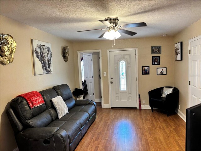 entryway with baseboards, a ceiling fan, wood finished floors, and a textured ceiling