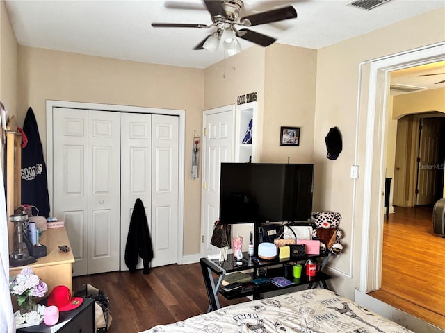 bedroom featuring dark wood-style floors, visible vents, arched walkways, a closet, and ceiling fan