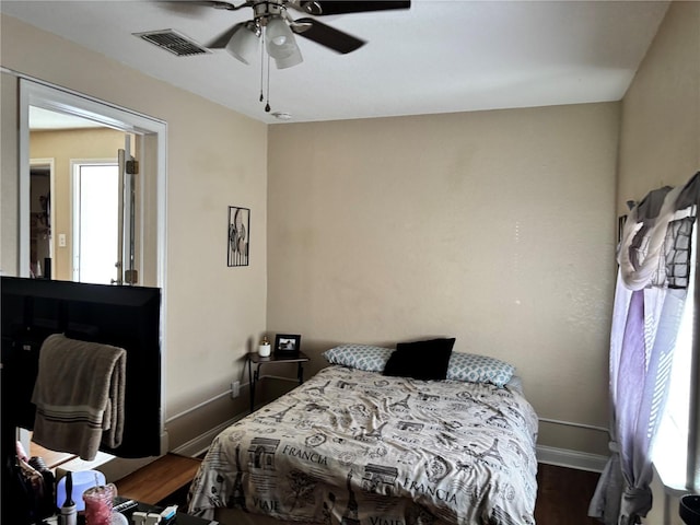 bedroom with baseboards, wood finished floors, multiple windows, and visible vents