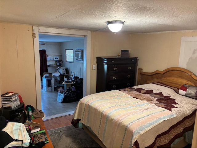 bedroom with wood finished floors, a textured ceiling, and a wall unit AC