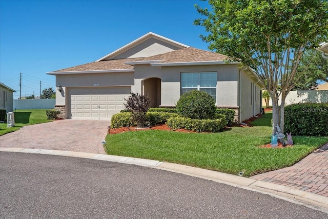 ranch-style house featuring an attached garage, a front lawn, stucco siding, and decorative driveway
