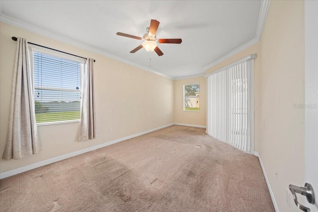 carpeted empty room featuring a ceiling fan, baseboards, and ornamental molding