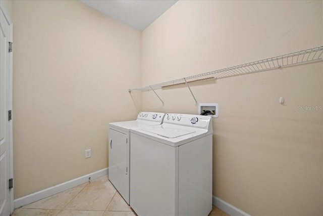 laundry room featuring washing machine and dryer, baseboards, light tile patterned flooring, and laundry area